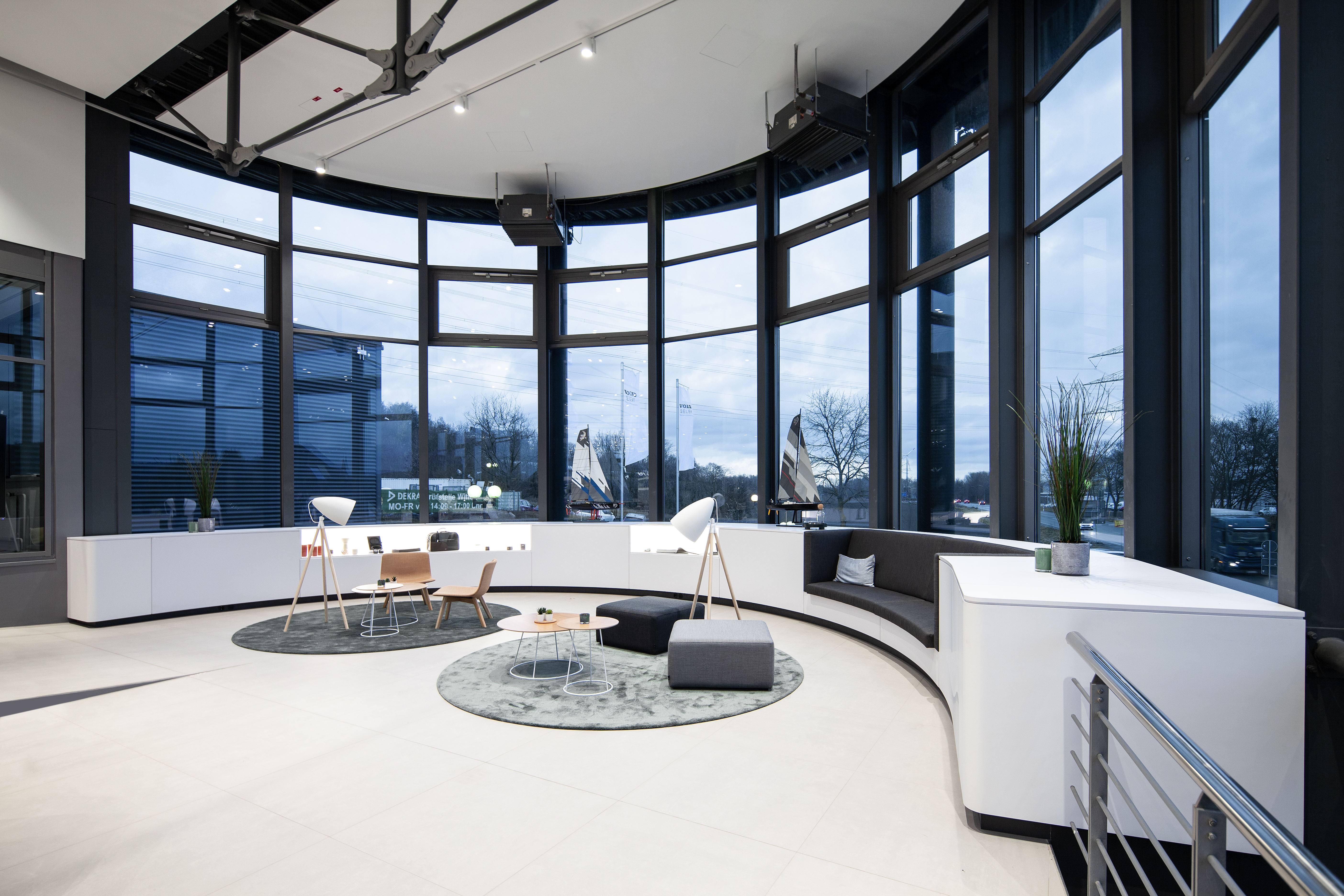 Lounge mit Sitzgruppen vor der raumhohen gebogenen Glasfassade